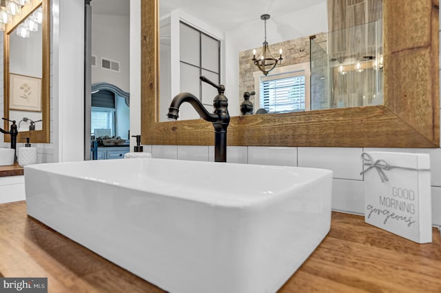 bathroom featuring a shower, an inviting chandelier, vanity, and hardwood / wood-style flooring