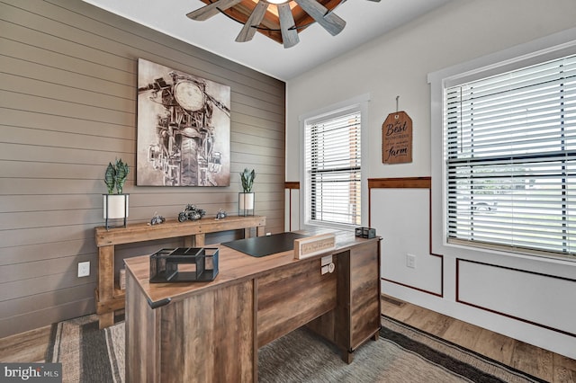 office space featuring wooden walls, ceiling fan, and dark hardwood / wood-style flooring