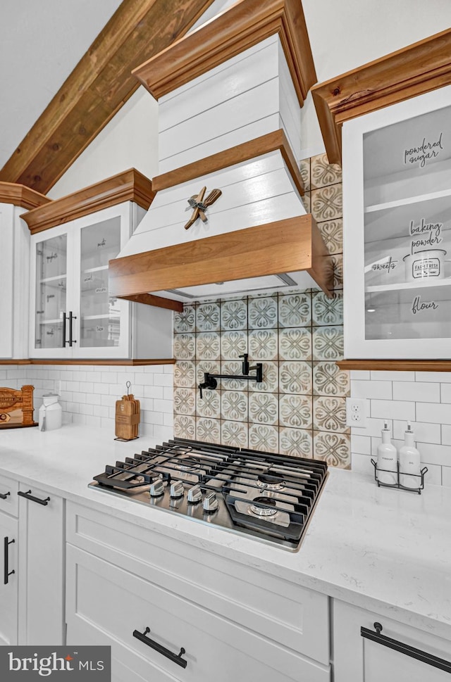 kitchen featuring white cabinets, backsplash, light stone countertops, and stainless steel gas stovetop