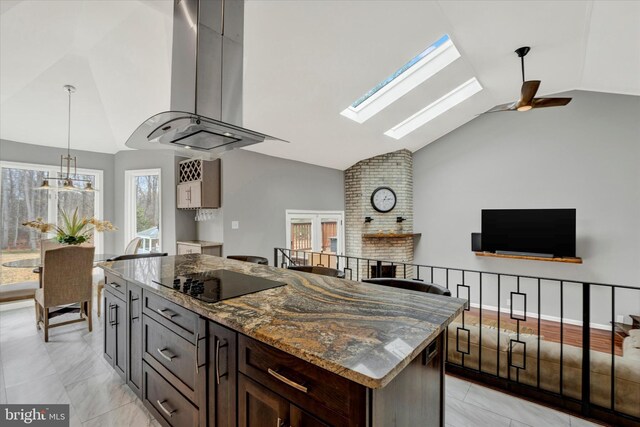 kitchen with dark stone counters, lofted ceiling with skylight, island exhaust hood, ceiling fan, and black electric stovetop