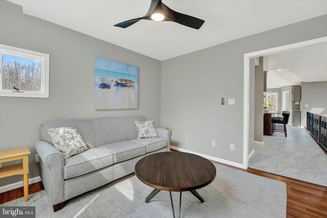 living area featuring baseboards and ceiling fan
