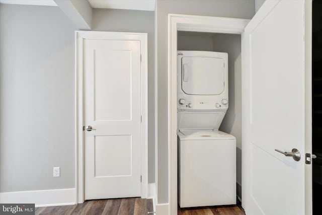 laundry area featuring wood finished floors, stacked washer and dryer, and laundry area