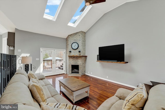 living room featuring baseboards, high vaulted ceiling, a skylight, wood finished floors, and a fireplace