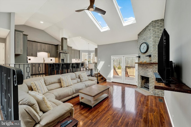 living area featuring a skylight, high vaulted ceiling, dark wood-type flooring, and ceiling fan