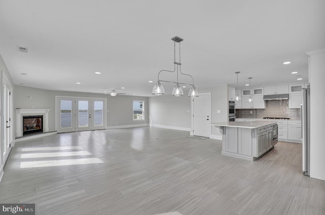 kitchen featuring appliances with stainless steel finishes, hanging light fixtures, a kitchen island, ceiling fan, and white cabinets