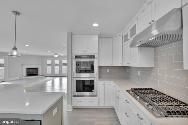 kitchen with pendant lighting, tasteful backsplash, ceiling fan, stainless steel appliances, and white cabinetry