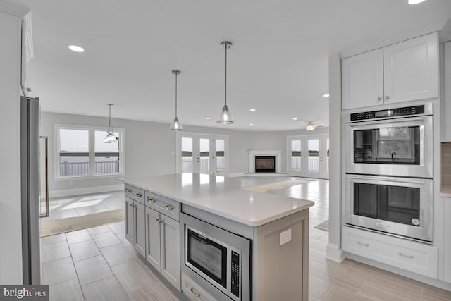 kitchen featuring a center island, french doors, appliances with stainless steel finishes, white cabinetry, and hanging light fixtures