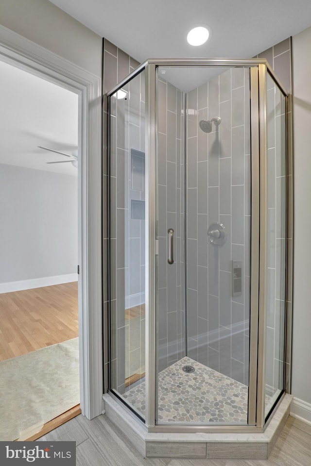 bathroom featuring a shower with door, ceiling fan, and hardwood / wood-style floors