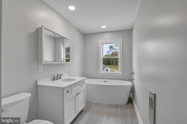 bathroom with toilet, vanity, and a tub