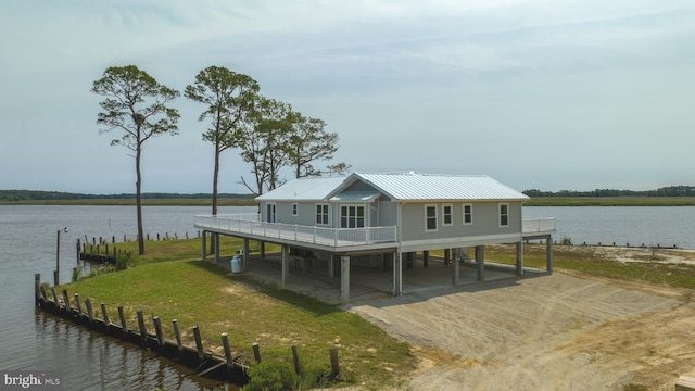 view of dock with a patio area, a lawn, and a water view