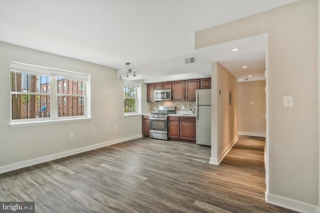 kitchen with pendant lighting, backsplash, dark hardwood / wood-style floors, and stainless steel appliances