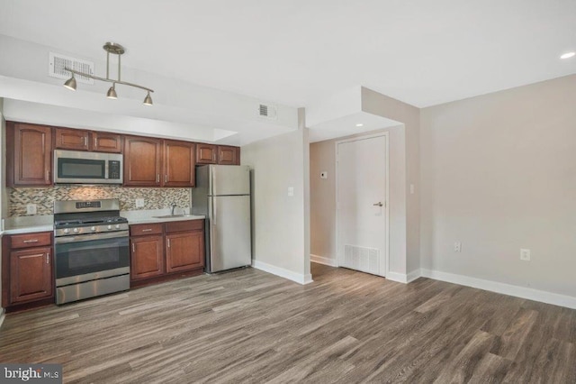 kitchen with appliances with stainless steel finishes, backsplash, dark wood-type flooring, and sink