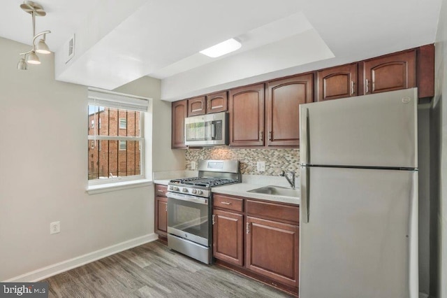 kitchen with white fridge, range with gas stovetop, light hardwood / wood-style flooring, backsplash, and sink