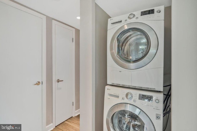 laundry area with light hardwood / wood-style flooring and stacked washer / drying machine