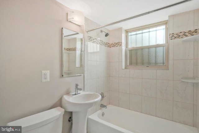 bathroom with tiled shower / bath combo and toilet