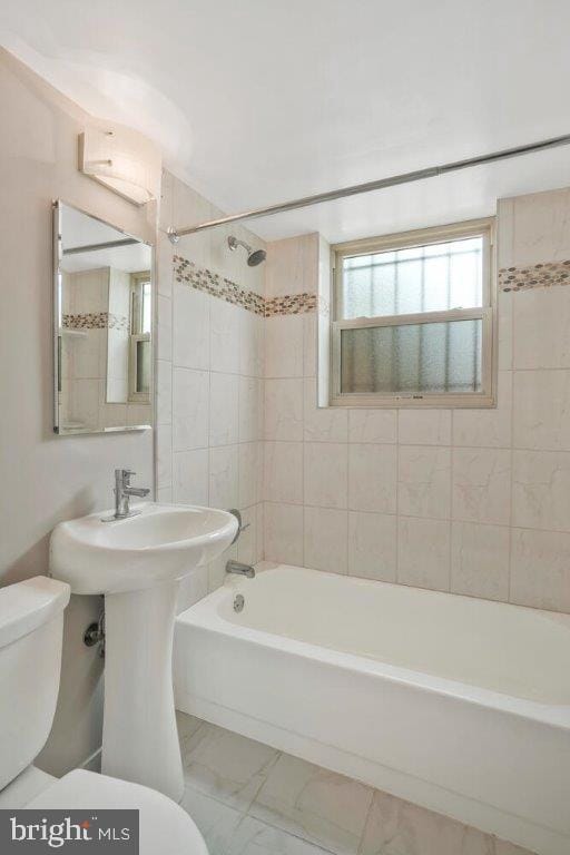 bathroom featuring tile flooring, toilet, and tiled shower / bath