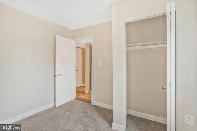 unfurnished bedroom with a closet and light carpet