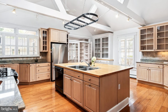 kitchen featuring tasteful backsplash, black dishwasher, rail lighting, wooden counters, and a kitchen island with sink