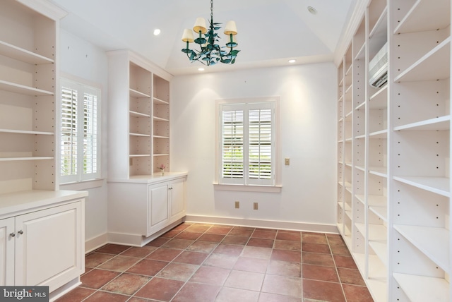 interior space featuring an inviting chandelier, dark tile floors, and lofted ceiling