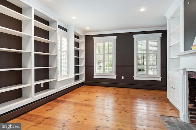 interior space with ornamental molding, a baseboard heating unit, and wood-type flooring