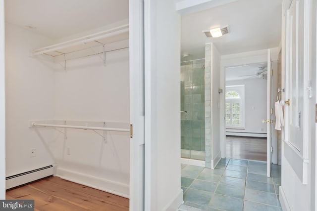 walk in closet with ceiling fan, a baseboard radiator, and light tile floors