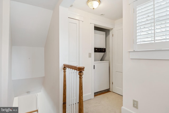 hall featuring stacked washer and dryer, light carpet, and vaulted ceiling