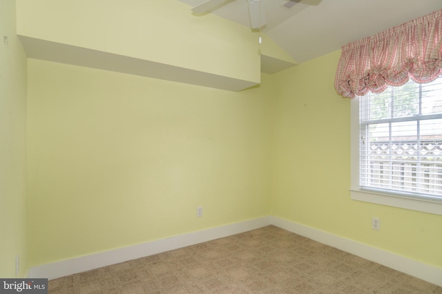 empty room featuring ceiling fan, light carpet, and vaulted ceiling