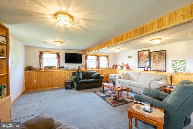 carpeted living room with a wealth of natural light, wooden walls, and a textured ceiling