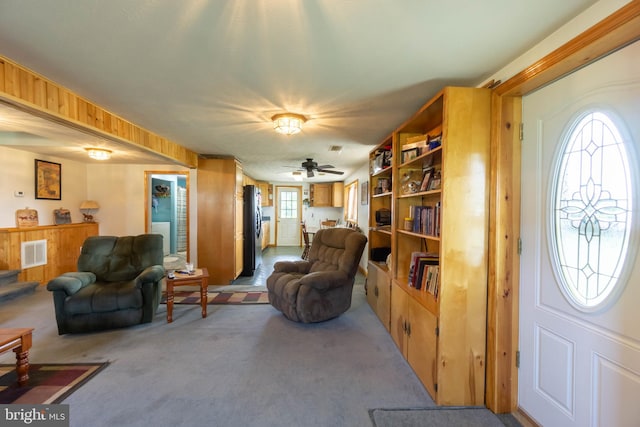 living room featuring wood walls, carpet floors, and ceiling fan