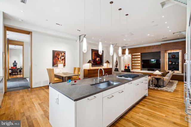 kitchen featuring light hardwood / wood-style floors, decorative light fixtures, sink, white cabinets, and stainless steel gas cooktop