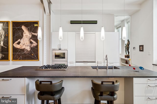 kitchen with white cabinetry, stainless steel gas cooktop, double oven, sink, and pendant lighting