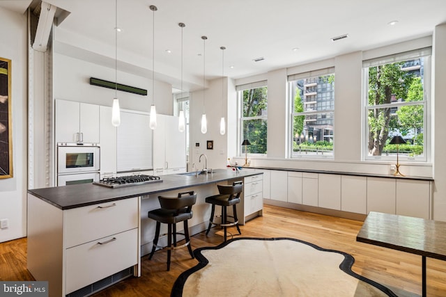 kitchen with pendant lighting, a center island, light hardwood / wood-style flooring, and white cabinetry