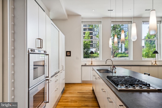 kitchen with sink, a healthy amount of sunlight, light hardwood / wood-style floors, and pendant lighting