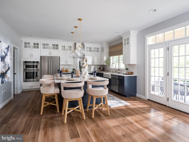 kitchen featuring hanging light fixtures, stainless steel appliances, a kitchen breakfast bar, white cabinets, and a kitchen island