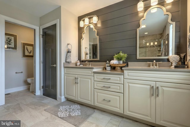 bathroom featuring tile flooring, toilet, a tile shower, vanity with extensive cabinet space, and double sink