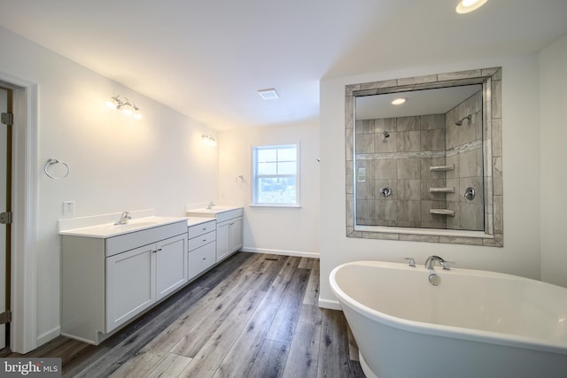 bathroom with double vanity, hardwood / wood-style flooring, and tiled shower