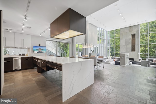 kitchen with white cabinetry, kitchen peninsula, light stone counters, and rail lighting