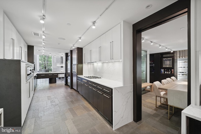 kitchen featuring backsplash, dark brown cabinetry, white cabinetry, and stainless steel gas stovetop