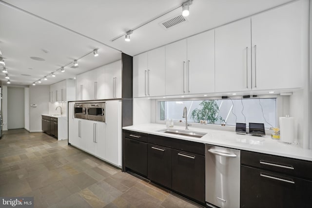 kitchen with track lighting, white cabinetry, and sink