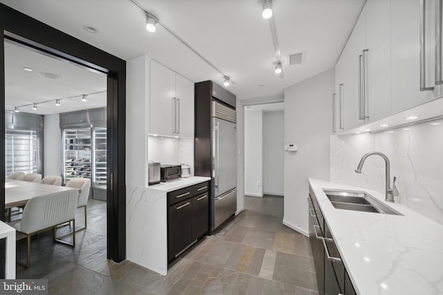 kitchen featuring white cabinetry, built in fridge, and sink