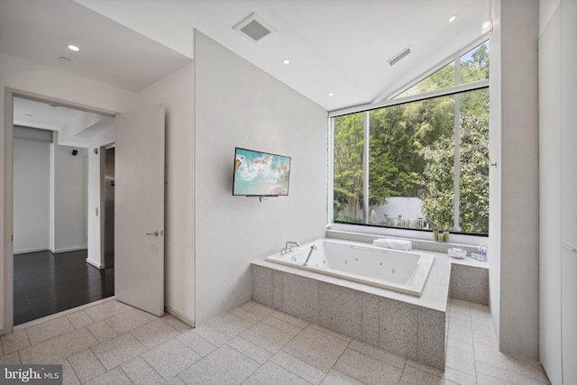 bathroom with tiled tub and vaulted ceiling