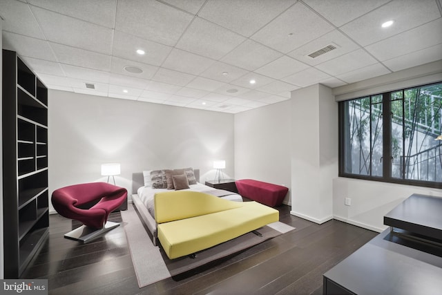 living room with a drop ceiling and dark wood-type flooring