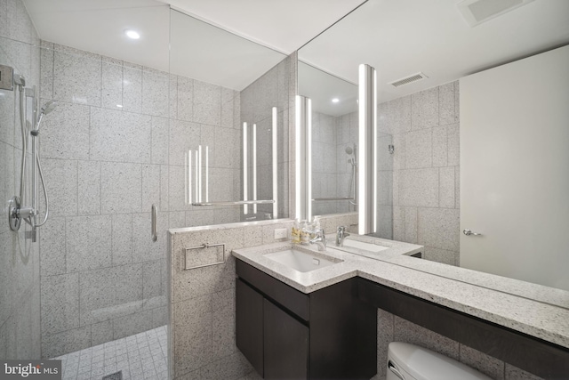 bathroom featuring walk in shower, vanity, toilet, and tile walls