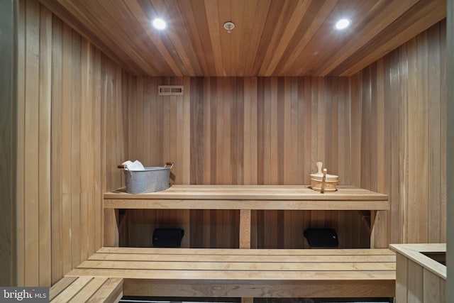 view of sauna featuring wooden ceiling and wooden walls