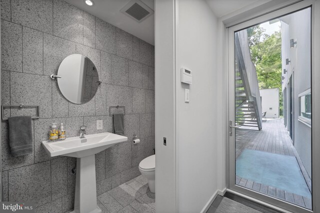 bathroom featuring hardwood / wood-style floors, tile walls, and toilet