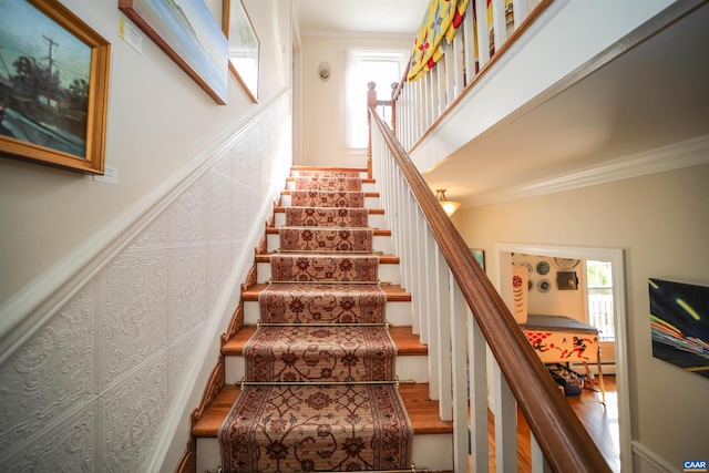 stairs with ornamental molding and hardwood / wood-style flooring