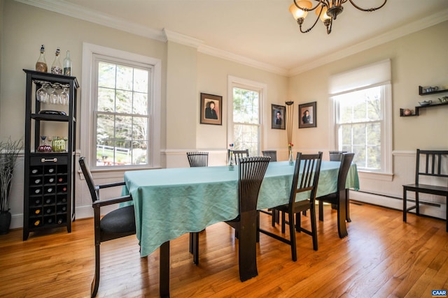 dining space featuring a notable chandelier, ornamental molding, a healthy amount of sunlight, and light wood-type flooring