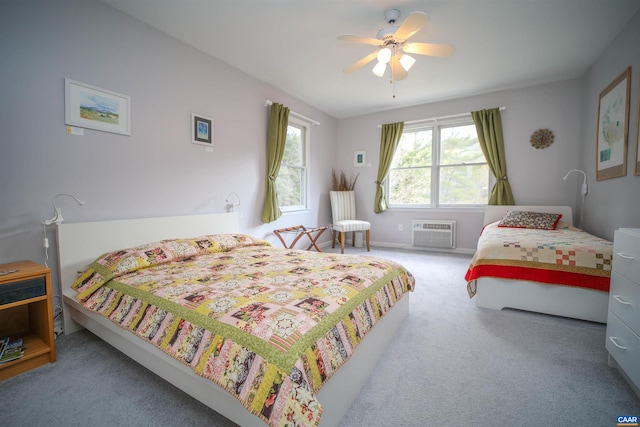 bedroom with a wall mounted AC, light colored carpet, and ceiling fan