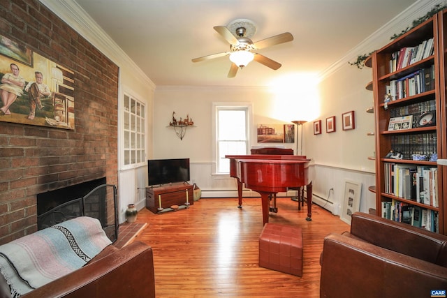 sitting room with ceiling fan, crown molding, light hardwood / wood-style floors, a fireplace, and baseboard heating