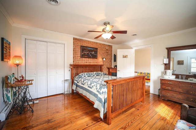 bedroom with light hardwood / wood-style floors, a closet, ceiling fan, and a brick fireplace